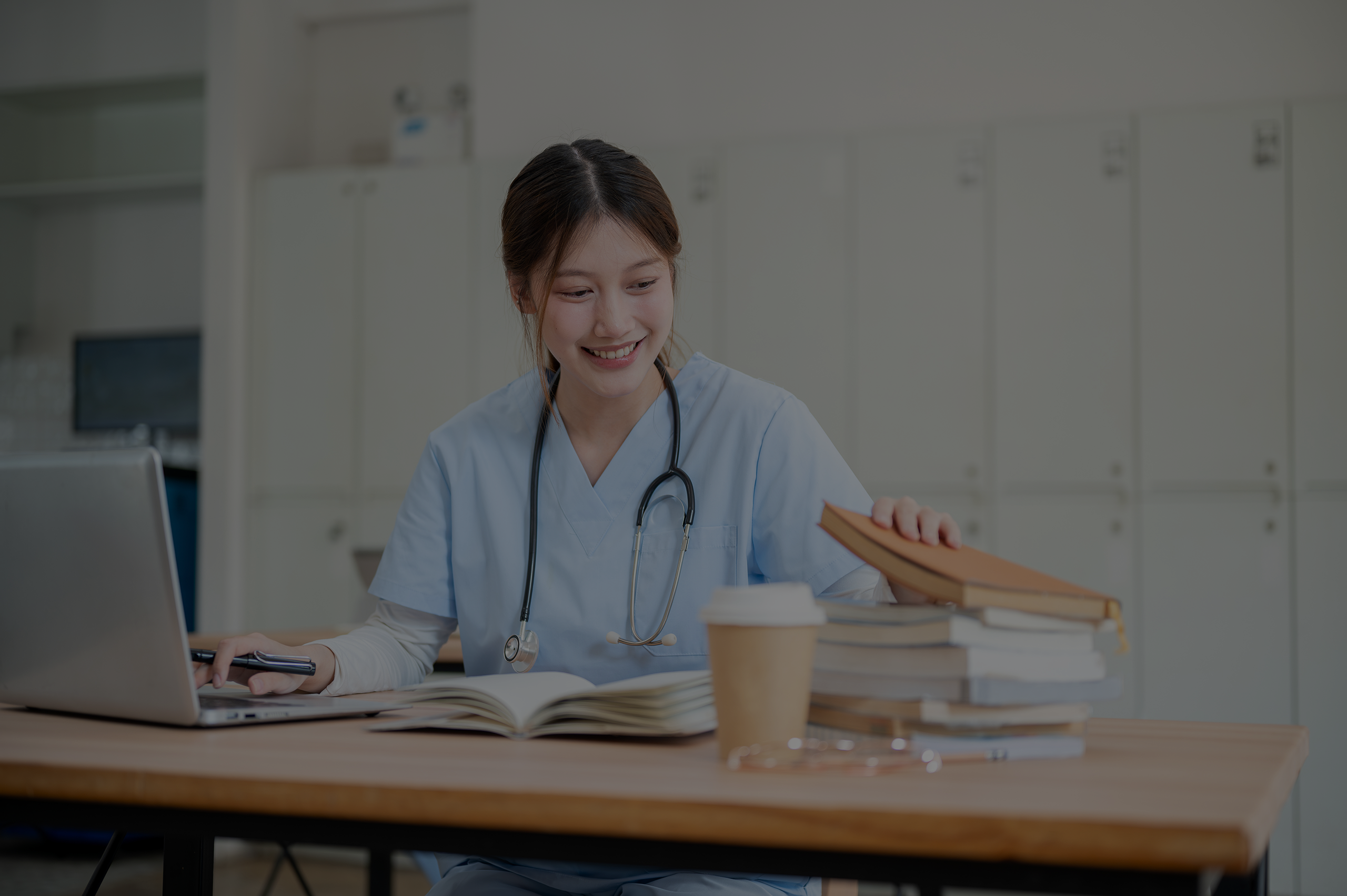 Female student at a desk with books and laptop